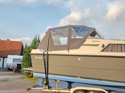 Ein Motorboot mit einem grauen Verdeck, auf einem Trailer geparkt.