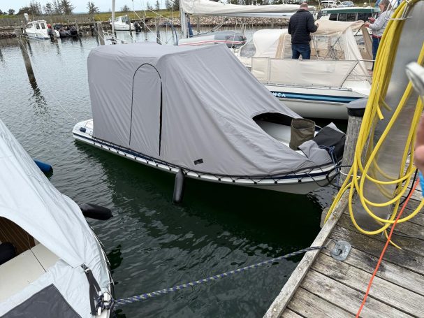 Ein mit einem grauen Schutzüberzug bedecktes Boot im Hafen.